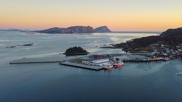 Fabrikken i Kalvåg nede ved vannet med fjell i bakgrunn